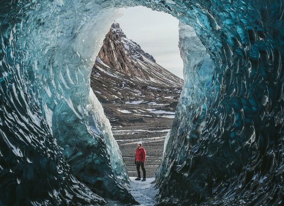Eishöhle mit Mensch in roter Outdoorjacke am Vatnajökull in Island