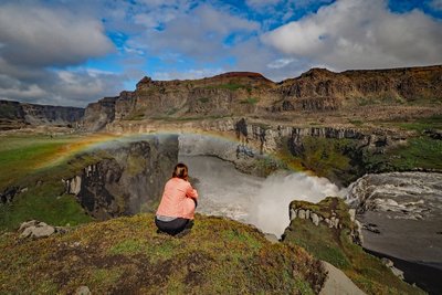 Wanderin am Wasserfall Hafragilsfoss mit Regenbogen