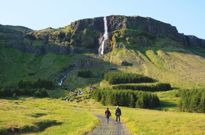 zwei Personen laufen auf einen Wasserfall zu