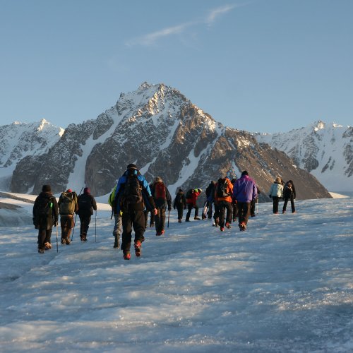 Eine Gruppe Menschen läuft über eine vereiste Fläche in Spitzbergen