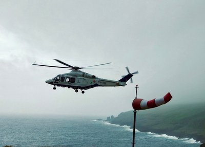 Hubschrauber fliegt von rechts nach links, eine Windhose hzeigt sehr stürmisches Wetter an.