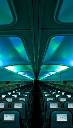 Flüge für Island Reisen - Innenraum eines Passagierflugzeugs mit blaugrünlicher Nordlicht-Beleuchtung
