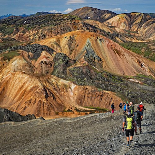 Wandergruppe laufen auf einem Bergkamm. Alle sind in Outdoorkleidung mit Rucksäcken. 