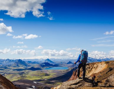 Eine Person in Outdoorkleidung schaut über die bergige Landschaft Islands