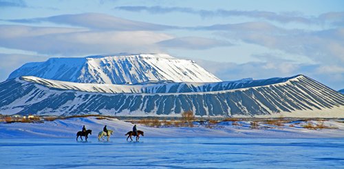 Drei Reiter auf dem gefrorenen See Myvatn im Norden Islands. ImHintergrund ist der Berg Hverfell zu sehen. 