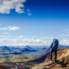 Eine Person in Outdoorkleidung schaut über die bergige Landschaft Islands