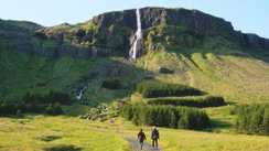 zwei Personen laufen auf einen Wasserfall zu