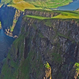 Typisch für die Färöer-Inseln - Steile, zerklüftete, grün bewachsene Klippen