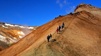 Island Urlaub in Minigruppen - Eine Urlaubergruppe wandert auf einen bunten Rhyolithberg