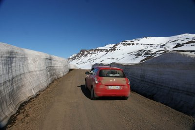 Island-Rundreise im Frühjahr Im isländischen Frühling auf einer Autorundreise - Eine Passstraße mit Schneewänden in den Ostfjorden