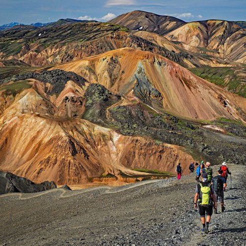 Wandergruppe laufen auf einem Bergkamm. Alle sind in Outdoorkleidung mit Rucksäcken. 