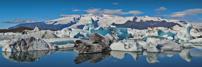 Ein Traum im Island Urlaub - Schwimmende Eisberge vor vergletschertem Vulkanberg